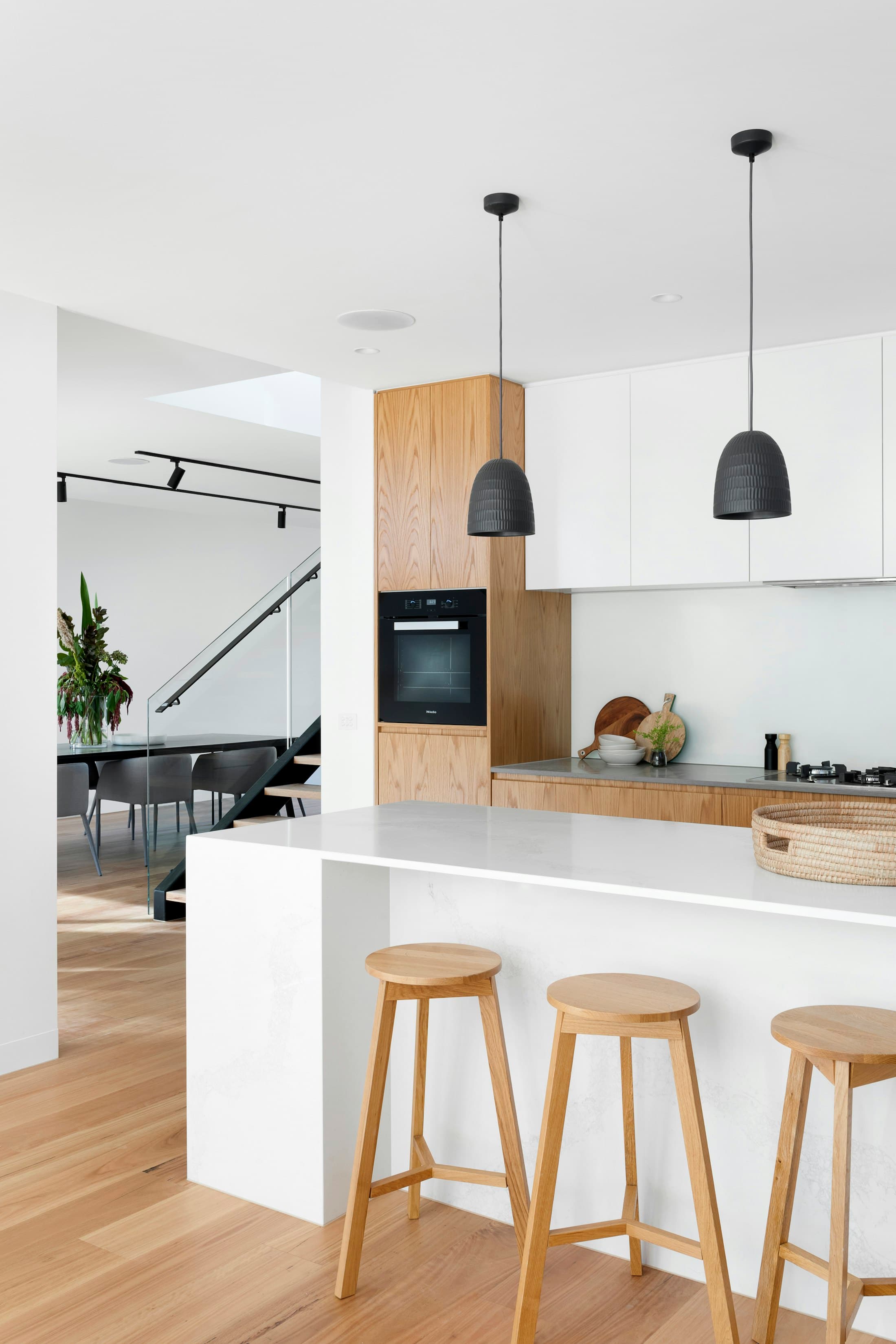 The kitchen island in oak and stone — the working heart of the plan, set one step below the dining terrace.
